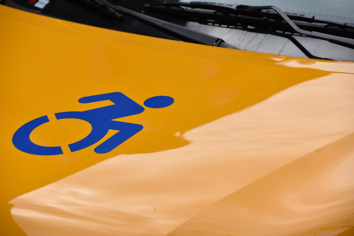 Close up shot of a wheelchair accessibility symbol on a yellow taxi.