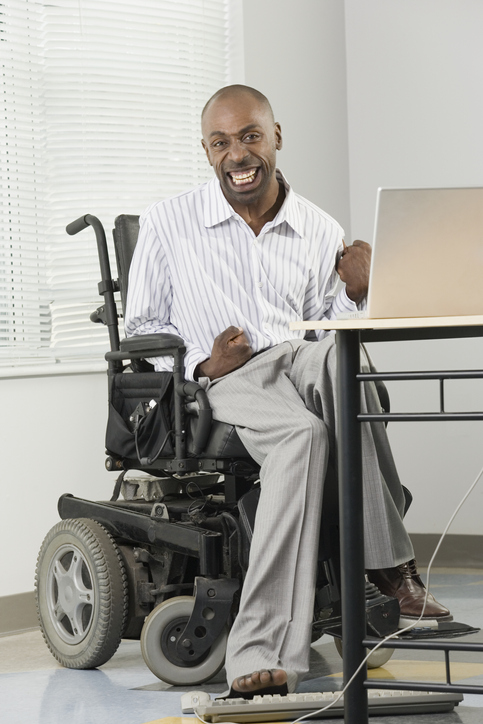 • Image of a businessman with Cerebral Palsy sitting in a wheelchair and working on a computer with his foot